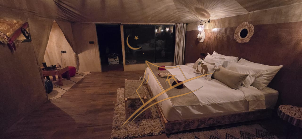 Spacious tent suite with a private sitting nook, mirror and desert view through the window