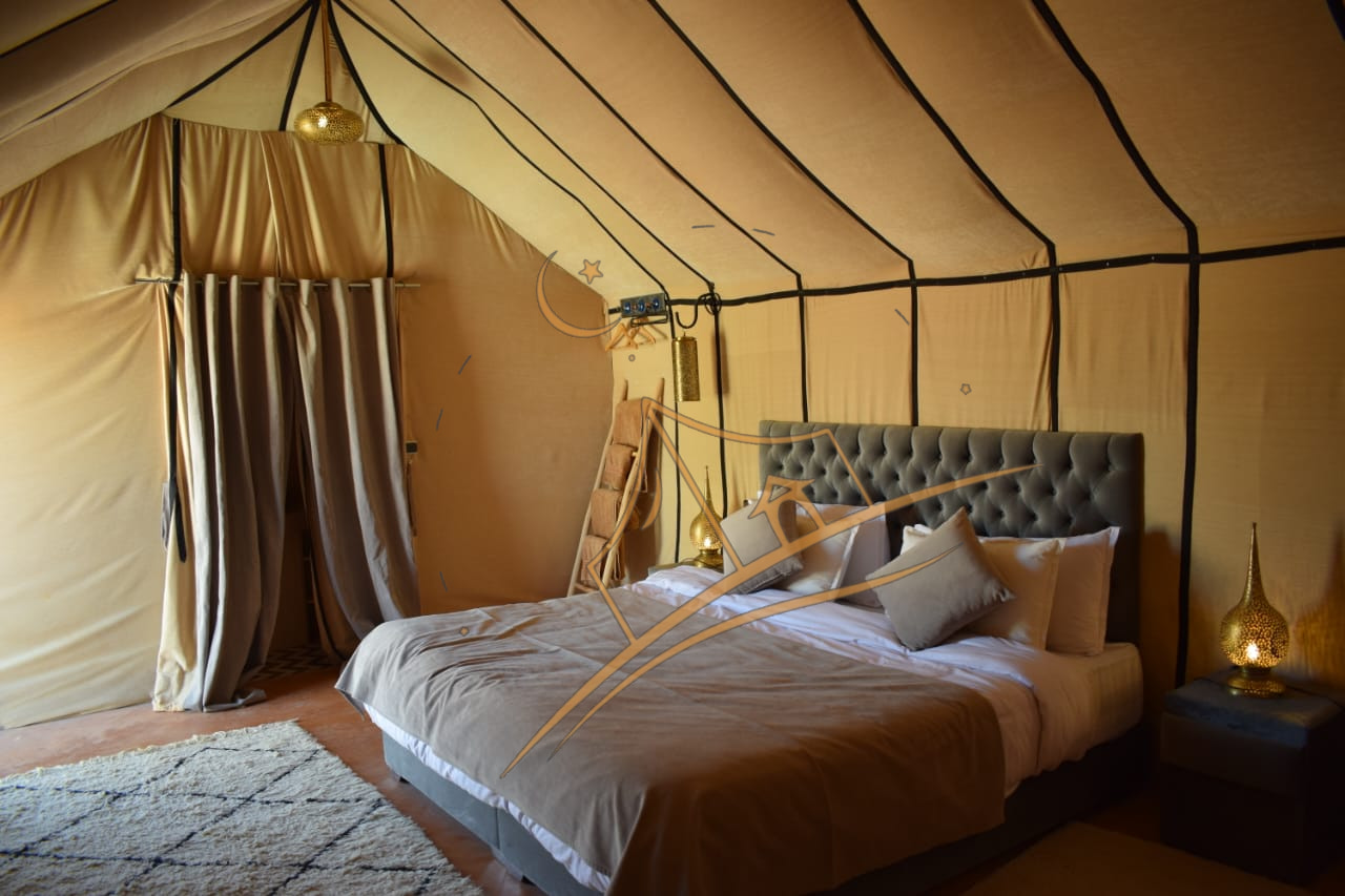 Gray tufted headboard with daylight streaming through a luxury tent's canvas walls