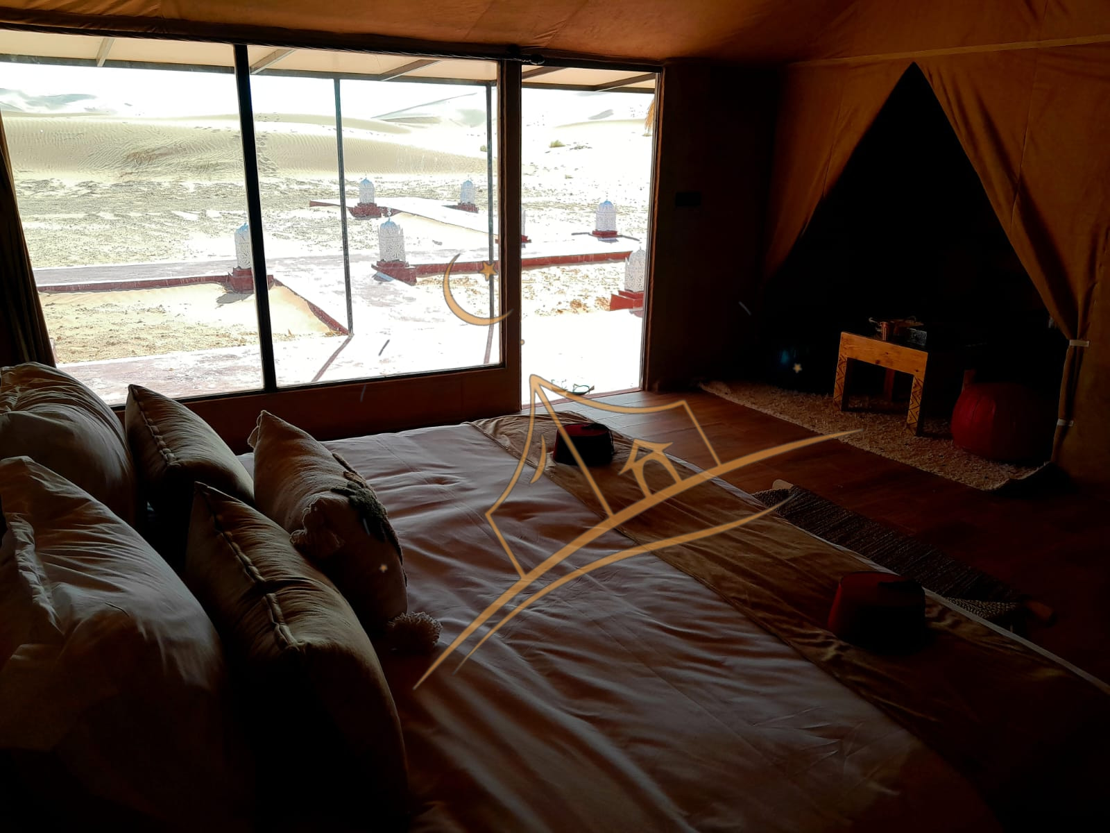 Golden Erg Chebbi dunes seen through floor-to-ceiling windows beside a guest bed