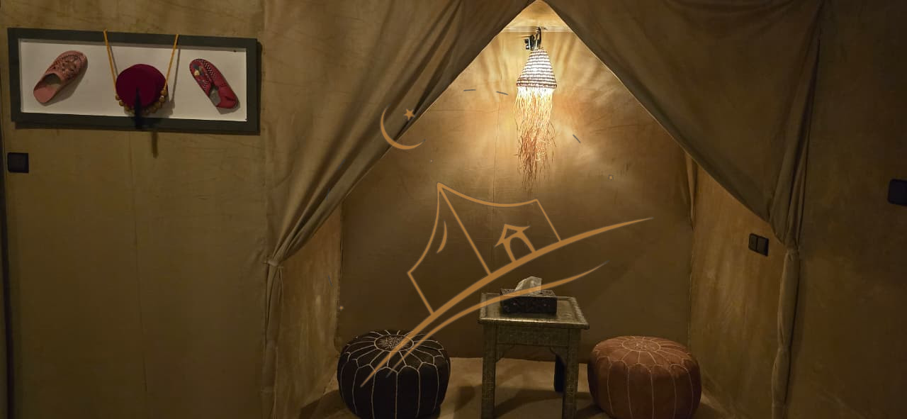 Moroccan sitting nook with a beaded pendant lamp and leather poufs beside a display of traditional slippers