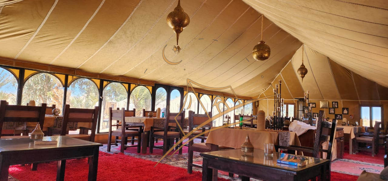 Sunlit dining tent with arched Moroccan windows, brass pendant lamps and red carpets