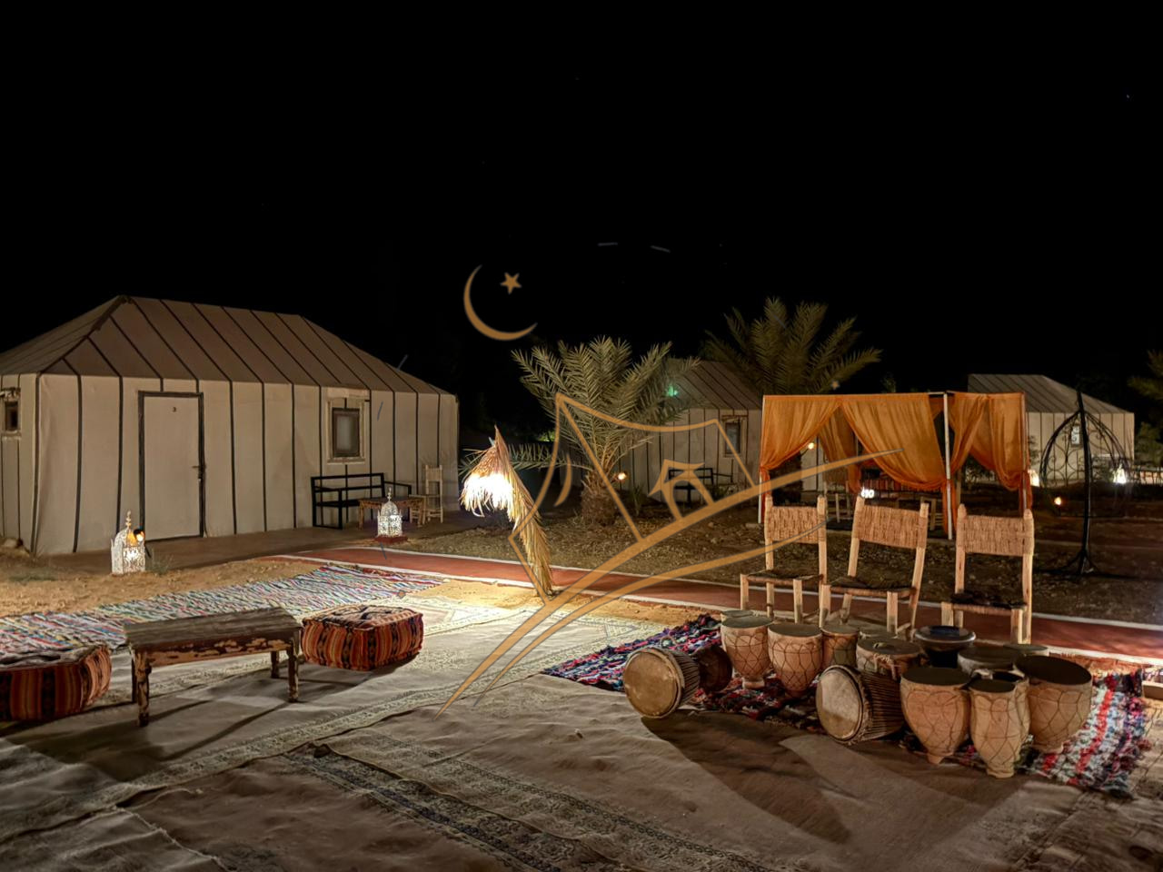 Traditional Berber drums arranged beside a lantern-lit lounge tent at night