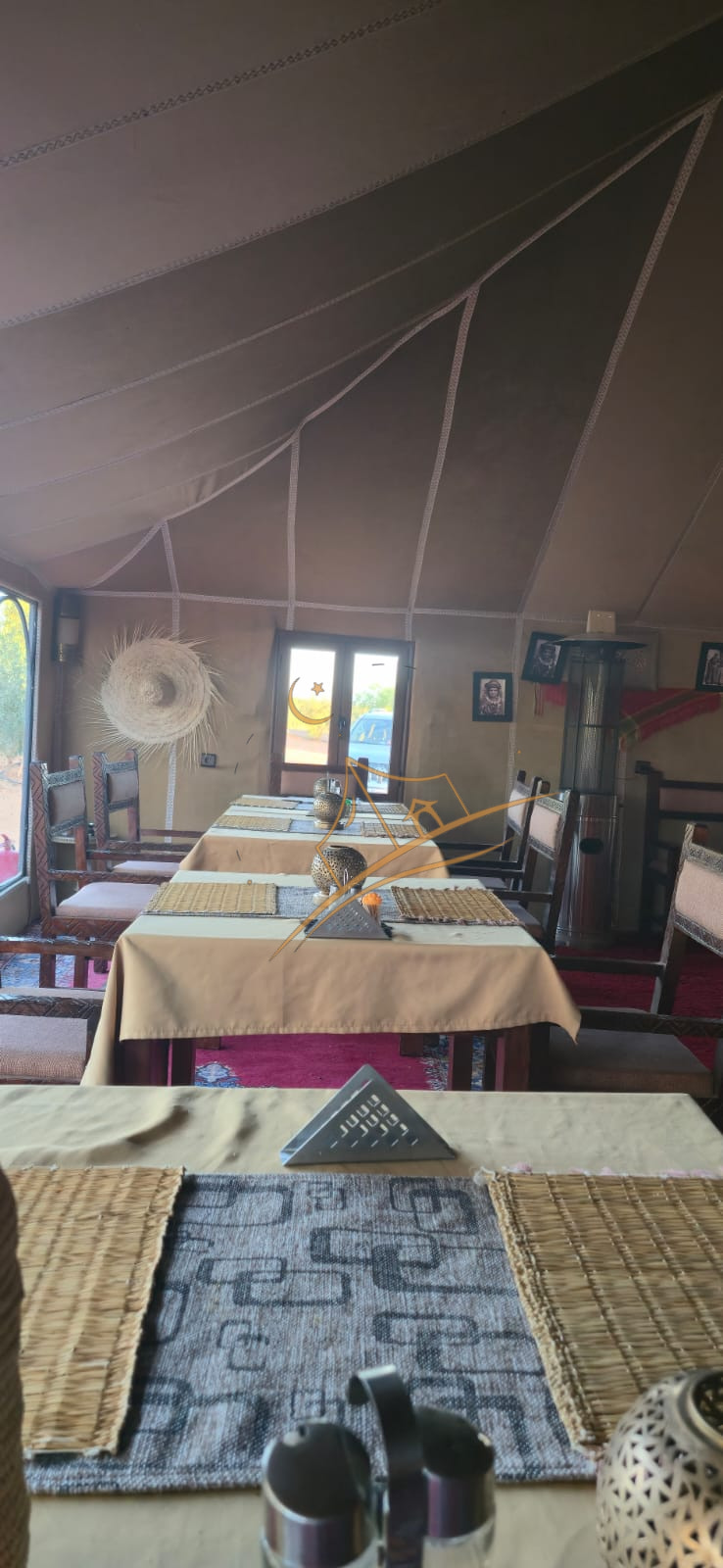 Sunlit dining tent set with woven placemats and traditional Moroccan tableware