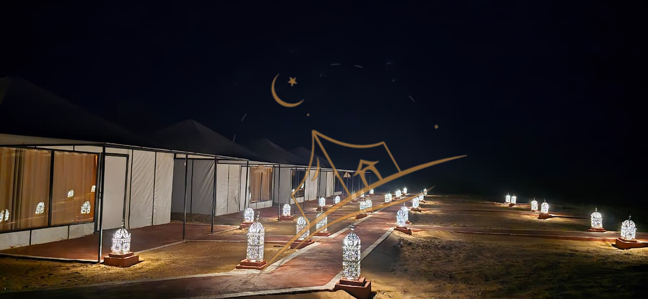 Long row of illuminated tents bordered by ornate lanterns stretching into the desert night