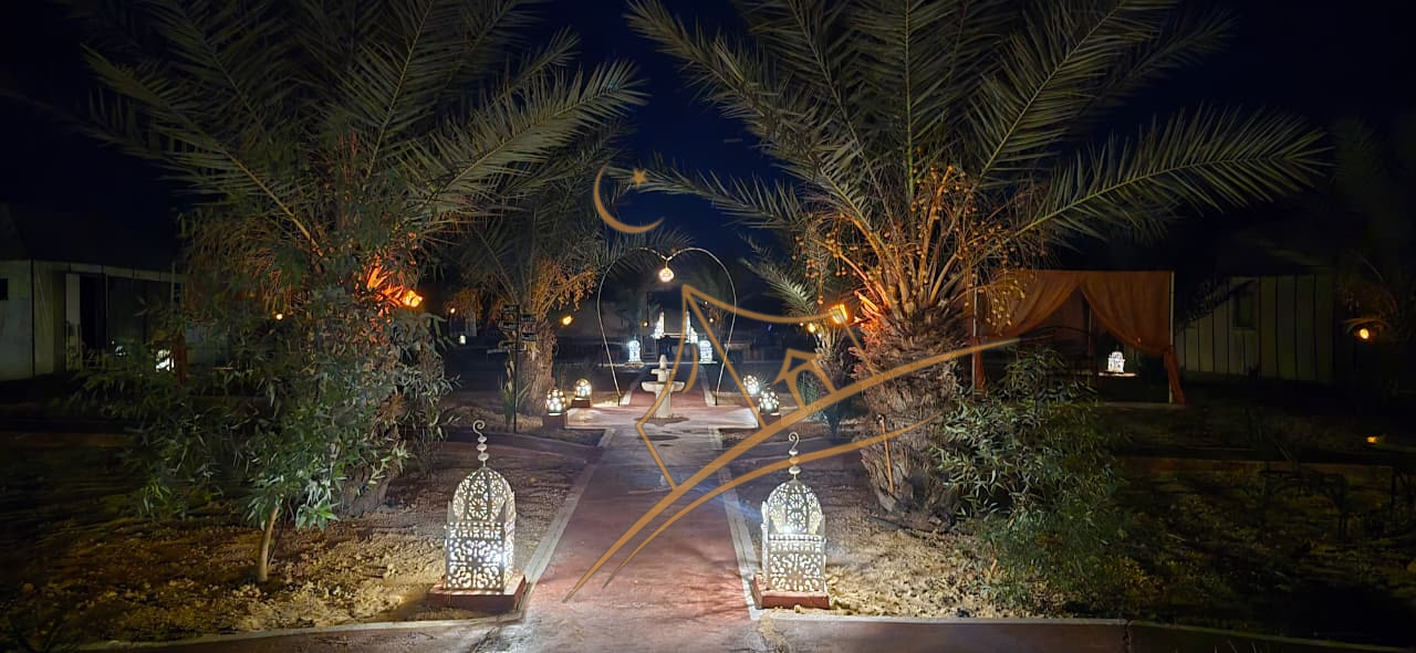 Palm-lined walkway leading to the camp's heart-shaped fountain arch at night